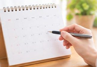 卓上カレンダーに予定を書き込む手元